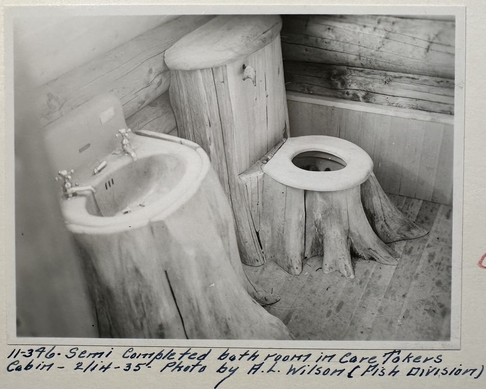 A sink and a toilet set on cedar stumps in the semi-completed bathroom