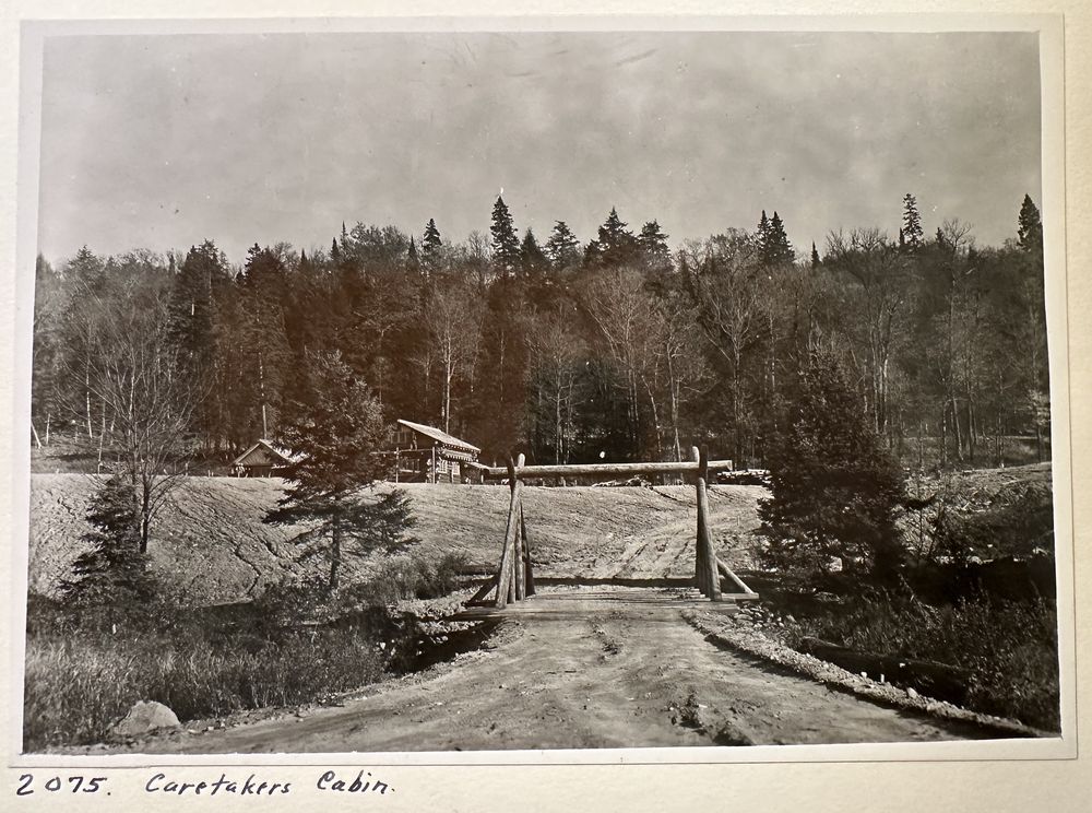 A dirt road and rustic log crossing leading toward the caretaker’s cabin