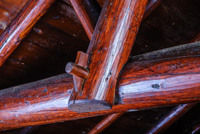 Close view of a log rafter joint where a squared tenon is locked with a round wooden peg
