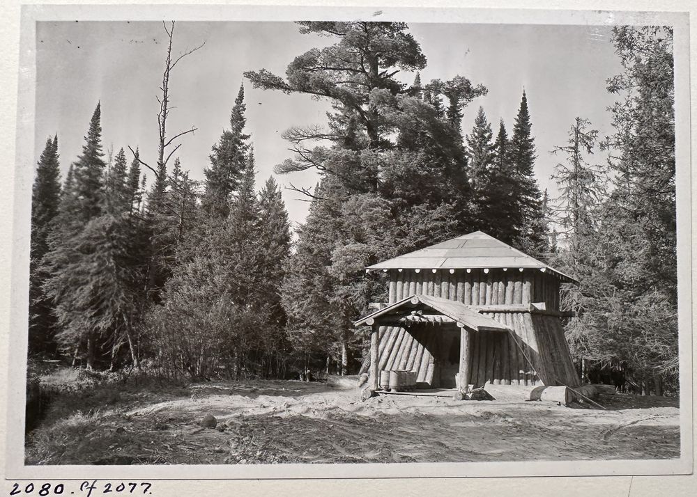 A log ice house with a hip roof standing in a clearing