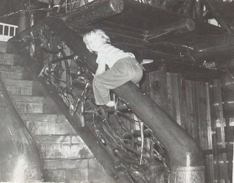 A child climbing on the root-work railing of the cabin staircase