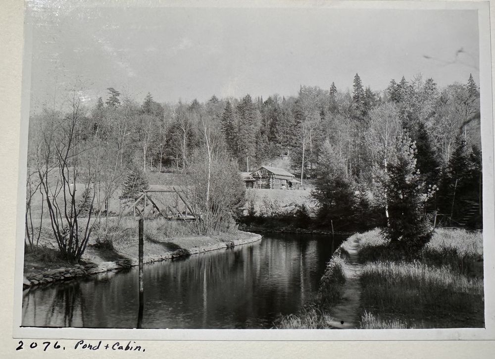 The caretaker’s cabin seen across a pond in late fall